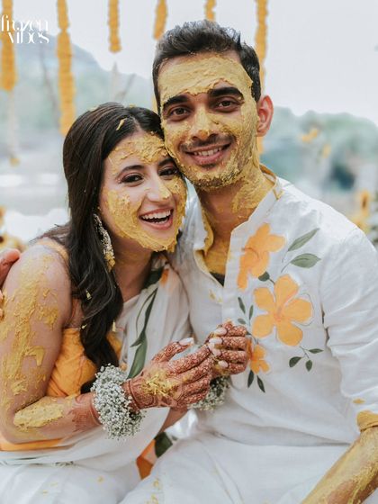 A joyful portrait of the couple covered in turmeric paste. These photos are all about capturing the uninhibited fun and vibrant energy of the Haldi.