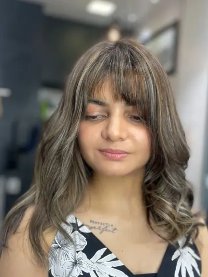 A trendy look featuring curtain bangs and ash-blonde highlights. This style is modern, fresh, and frames the face beautifully.