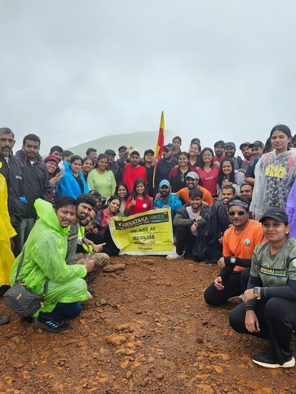 A large group of trekkers with the Karnataka flag and our banner, celebrating their achievement at Netravathi peak.