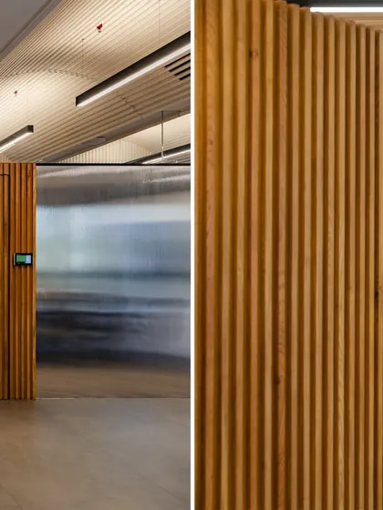 A detail from the revisited UTI HQ, showing the contrast between a translucent wall and the warmth of a vertically slatted wooden door, demonstrating how we update spaces for modern needs.