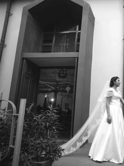 A classic black and white shot of a bride with a long, flowing veil outside a church. This image has a timeless, storybook quality.