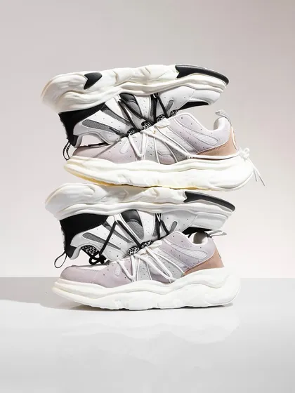 A creative stack of chunky white sneakers. This unconventional composition is eye-catching and modern, perfect for a social media campaign aimed at a younger, fashion-forward audience.