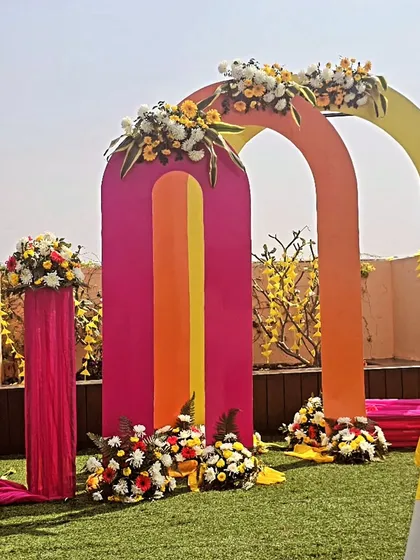 Planning a fun, modern haldi ceremony? We love playing with color, like these vibrant pink, orange, and yellow arches for a daytime garden event. This setup makes for incredible photos and a joyful atmosphere.