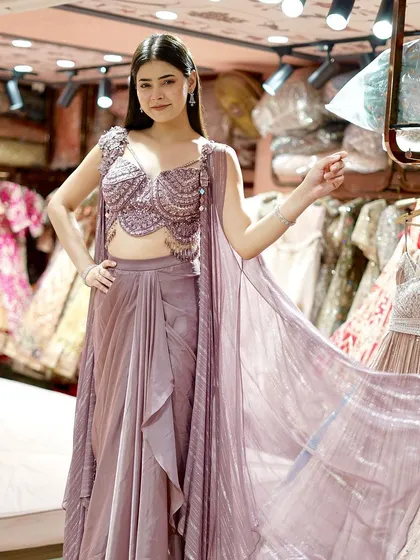 Elevate your style with this mauve dhoti-blouse set, complete with an embellished cape and dazzling mirror work.