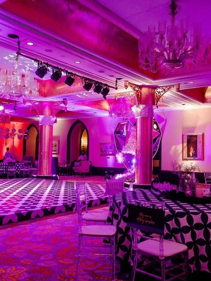 An overview of the Sangeet setup at the Taj Mahal Palace. The room's existing grand pillars were highlighted with purple uplighting, and the custom geometric-print tablecloths added a modern touch.