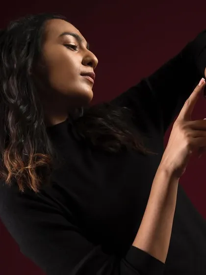 This shot for Crossbeats focuses on their smartwatch. The model's pose is directed to naturally draw the eye to the product on her wrist, showcasing its interface against a rich, dark background for a premium tech look.