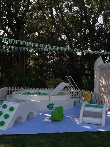 A dedicated soft play area for the youngest guests at the Tennis Club party. This safe and fun zone included a ball pit, a small slide, and ride-on toys, all in a clean white and green colour scheme.