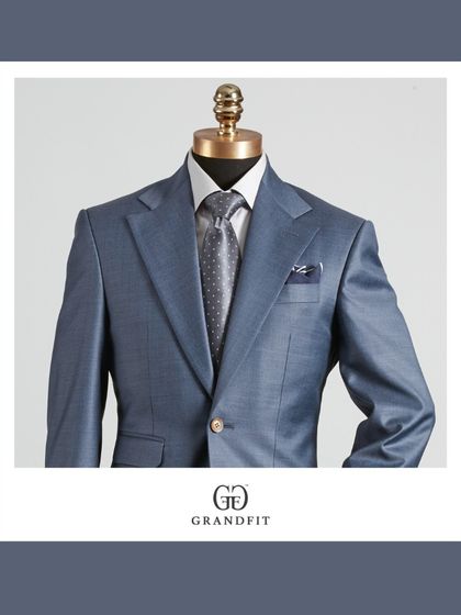 A detailed view of the light blue suit, highlighting the texture and the elegant pairing with a grey patterned tie and pocket square.