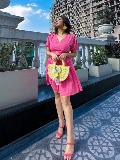 A different angle of the vibrant pink dress look. The matching pink block heels create an illusion of height and a cohesive monochromatic feel.