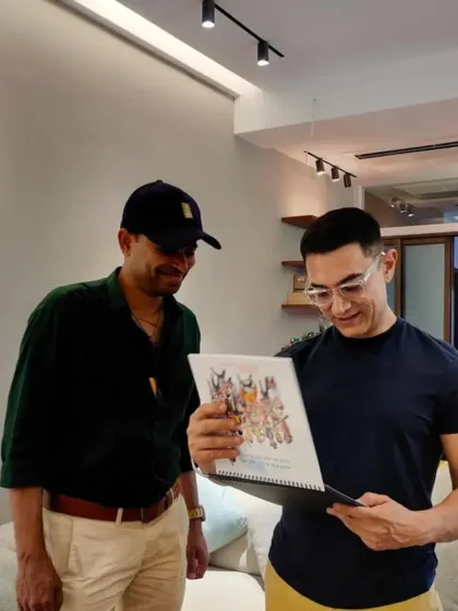 With Aamir Khan ji, looking at the calendar featuring caricatures of his film roles.