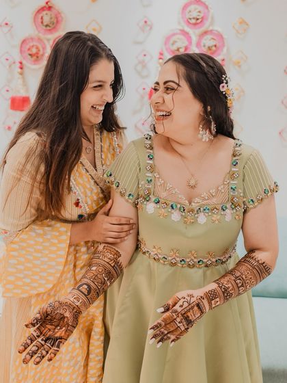 The bride sharing a laugh with her friend during her Mehendi ceremony. We focus on capturing the bonds of friendship and the happy, relaxed atmosphere.
