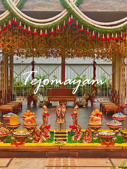 A grand and elegant setup for a baby shower, featuring a floral canopy and an extensive arrangement of traditional offering plates.