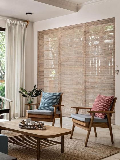 Another view of the living area, where the focus is on natural light and materials. The wooden armchairs and textured rug create a comfortable and relaxed atmosphere, perfect for conversation or quiet reading.