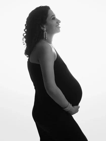 A high-key black and white silhouette. This technique uses a bright white background to create a clean, modern, and artistic profile of the expecting mother.