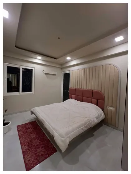 An in-progress shot of a bedroom featuring a curved, upholstered headboard against a fluted panel wall. This image shows the underlying structure and design before the final styling.