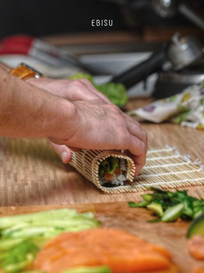 Crafting perfection, one roll at a time. Using a traditional bamboo mat, our chef expertly forms a sushi roll, a process that tells a story of culinary mastery and Japanese tradition.