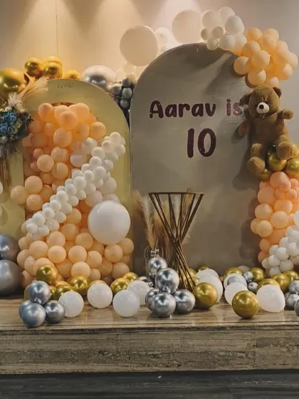 A soft and modern theme for a 10th birthday, using peach, silver, and gold balloons with a teddy bear accent.