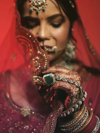 A close-up focusing on the bride's hands, showcasing her intricate mehndi, stunning ring, and the delicate fabric of her veil.