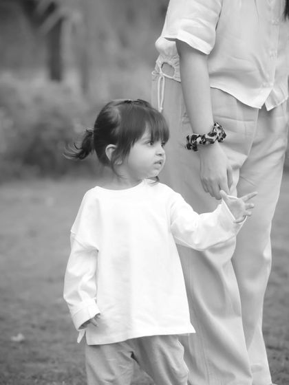 A toddler holding her mother's hand, captured in a simple and beautiful black and white composition.