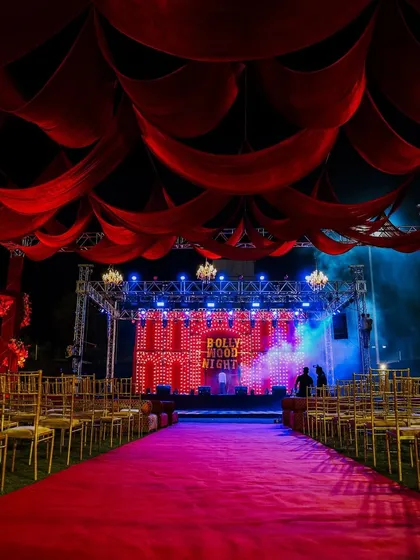 Your Bollywood dream, brought to life. We designed this Sangeet stage with a classic red carpet theme, complete with dramatic red drapes and a retro bulb backdrop, setting the stage for a night of filmy fun.