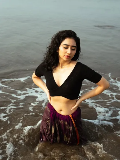 A unique concept of a saree in the sea. This shot captures the contrast of the wet, heavy fabric and the model's delicate pose in the water.