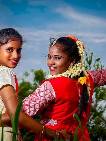 A fun and energetic shot of two friends during an outdoor puberty ceremony photoshoot. Her cheerful wave and their shared smile capture the celebratory spirit of the occasion.