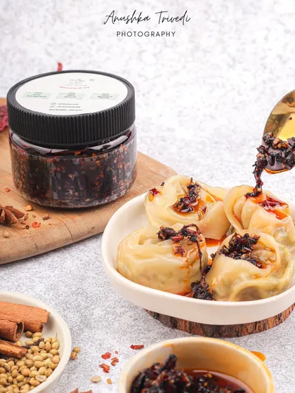Dumplings being drizzled with a spicy chili oil. This action shot is all about flavour, capturing the moment that adds a kick to the dish.