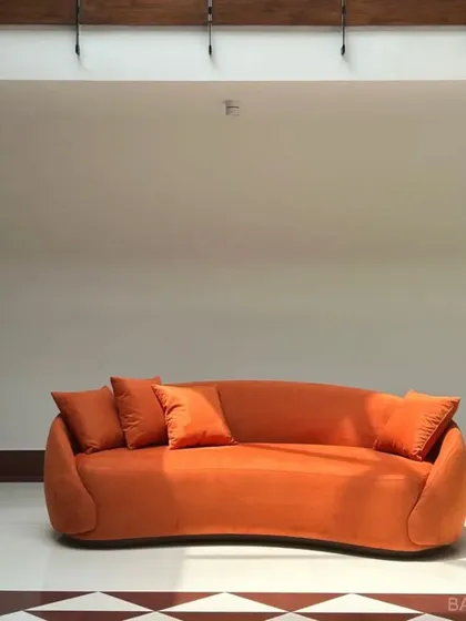 We love a bold color moment. This custom-curved sofa in a vibrant orange isn't just a piece of furniture; it's a statement. We work with you to pick fabrics and shapes that match your personality.