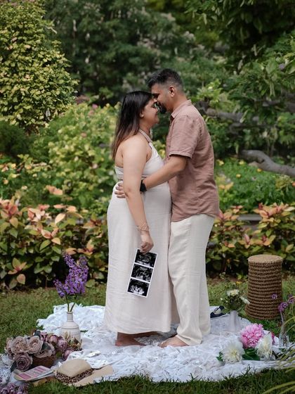 A standing portrait in a garden setting, with the mother-to-be holding her sonogram pictures.
