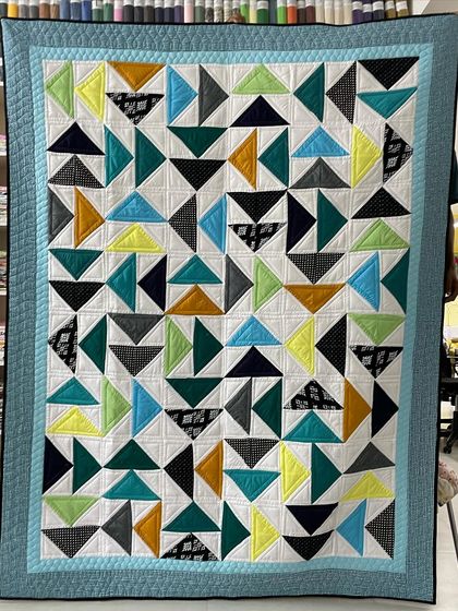 A "Twisted Geese" quilt with a playful, modern design in teal, yellow, and black.