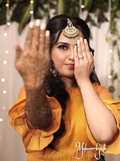 Chinmayi showing off her intricate mehendi design. Her makeup is fresh and radiant, perfect for the fun and festive atmosphere of a mehendi event.