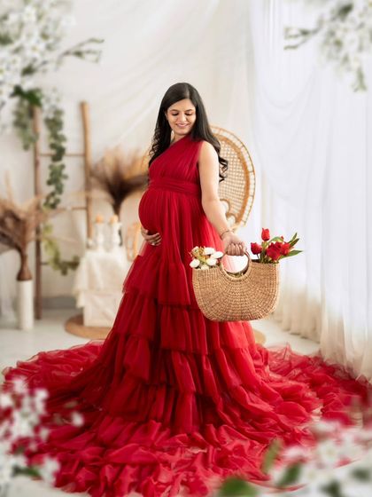 A charming portrait of a mom-to-be holding a basket of flowers, adding a fresh and lovely touch to the red gown shoot.