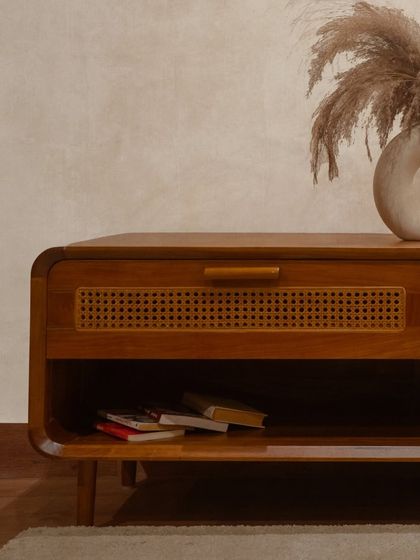 The 'Lobo' TV cabinet, styled with books and decor. It features a mix of open shelving and a drawer with a rattan front, offering versatile storage.