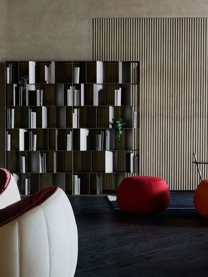 A study or library area with a modern, modular bookshelf as the centerpiece. The playful, rounded forms of the poufs and armchairs add a pop of color and personality.