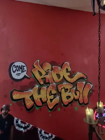 "Come Ride The Bull" lettering in a classic graffiti bubble style, part of the larger commercial mural project for the cafe.