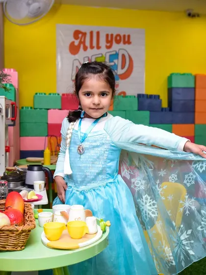 A little princess dressed as Elsa, striking a pose in our pretend play kitchen.