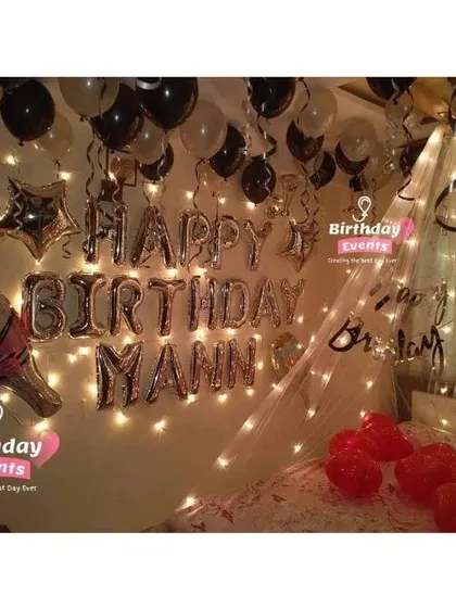 A personalized birthday surprise with a touch of celebration. This room features a fairy light canopy, "Happy Birthday Mann" in foil letters, and a fun champagne bottle foil balloon.