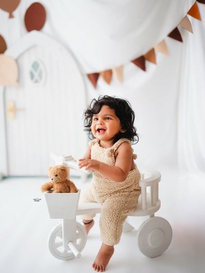 Riding his tricycle with his teddy bear in the basket. A fun and playful shot.