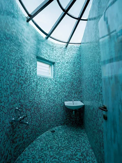Tactile beauty is central to our work. This spa-like bathroom is fully enveloped in vibrant blue mosaic tiles, with a curved wall and a skylight that floods the space with natural light, transforming a simple washroom into a dramatic, sensory experience.