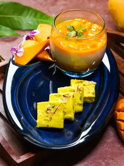 A modern take on Indian mango desserts, featuring a mango panna cotta and mango barfi on a vibrant blue plate. This shot beautifully blends traditional flavors with contemporary plating.
