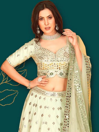 A closer look at the pastel green lehenga with intricate mirror work on the blouse. The subtle color and sparkling details are perfect for an elegant evening look.