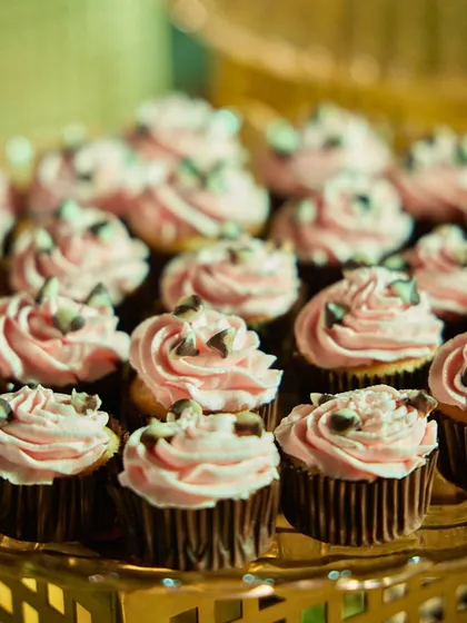 Rose-flavoured cupcakes with chocolate chip garnishes. The delicate pink frosting and rich chocolate make for a visually appealing and delicious sweet treat.