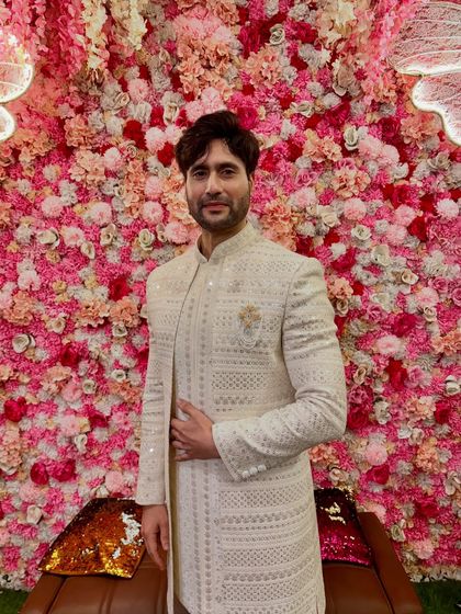 A closer look at the same off-white sherwani, highlighting the subtle gold brooch and the impeccable structure of the garment.
