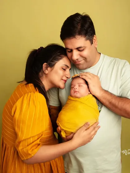 A quiet, tender moment between new parents and their baby. The focus here is on the emotional bond, with both parents cherishing their little one.