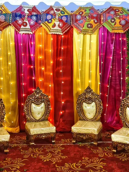 We bring the fun to pre-wedding events with vibrant stage decor. This mehndi setup uses a rainbow of colorful drapes, traditional umbrellas, and warm fairy lights to create a joyful and festive atmosphere for the celebration.