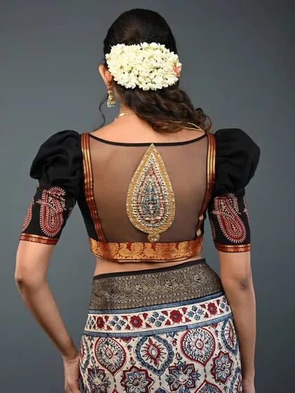 I love combining traditional elements with modern silhouettes. This black blouse features a sheer net back with an intricate, embroidered paisley motif, creating a look that is both elegant and alluring. The puffed sleeves add a touch of drama, making it a perfect choice for weddings and festive events.