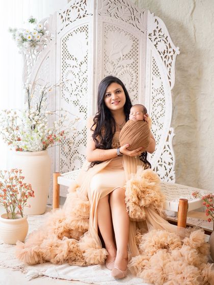 A glamorous mother poses with her newborn in an elegant studio setup. This shot shows how we can combine a beautiful maternal portrait with the newborn session.