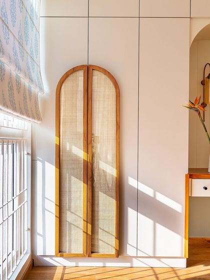 Sunlight streams through the window, highlighting the beautiful arched cane panels on this wardrobe door. It's a detail that adds warmth, texture, and a touch of modern farmhouse charm.