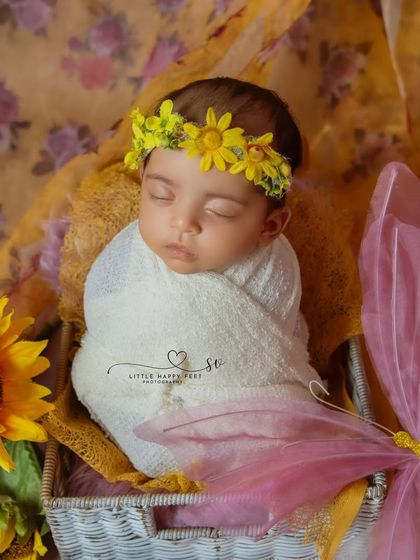 Radiant innocence. This baby girl, wrapped in white and surrounded by sunflowers and a pink butterfly, is a picture of summer joy.