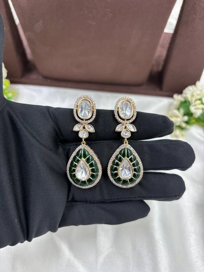 A beautiful Moissanite and AD necklace set with green or red Meenakari detailing. The combination of oval and teardrop stones gives this piece a unique and luxurious appeal.